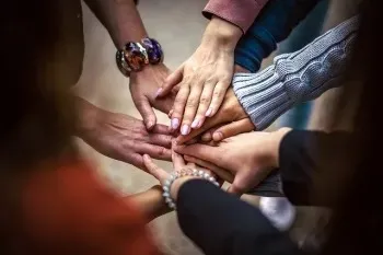 Circle of people putting their hands in the center.