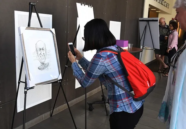 Attendees took photos and signed the Bruce Hammock illustration. (Photo by Kathy Keatley Garvey)