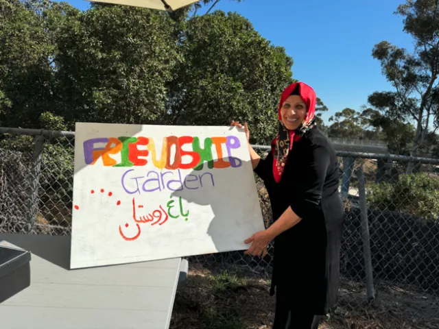 Shahnaz Roshanoi helps paint a welcome sign that says