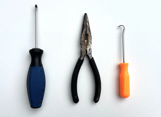 A screwdriver, a pair of pliers, and a pick tool with a sharp point.