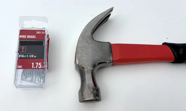 A hammer and a small container of #16 1.25” finishing nails