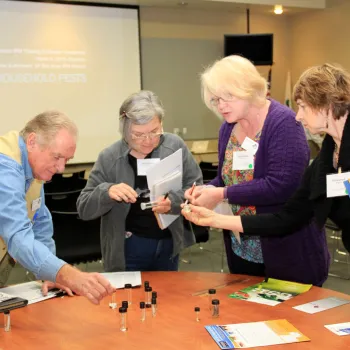 Volunteers leaning over a table looking at vials in a class.