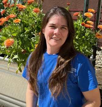 Master Gardener in blue shirt in front of orange flowers.